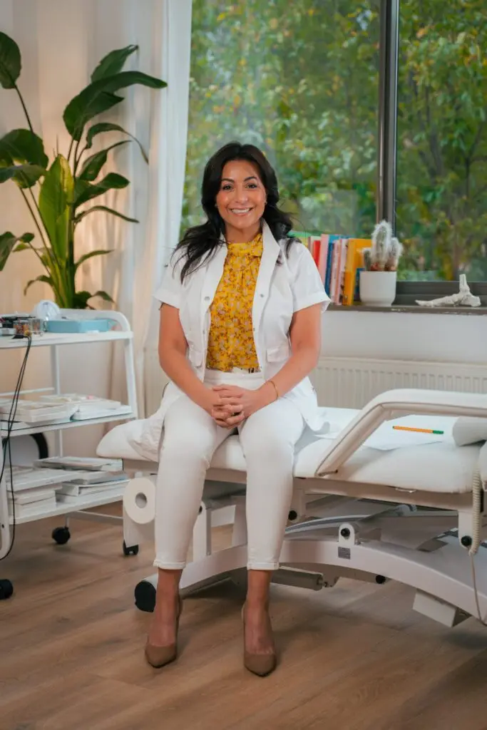 Adriana Guarín sitting on the treatment table at her integrative medicine clinic in Amsterdam